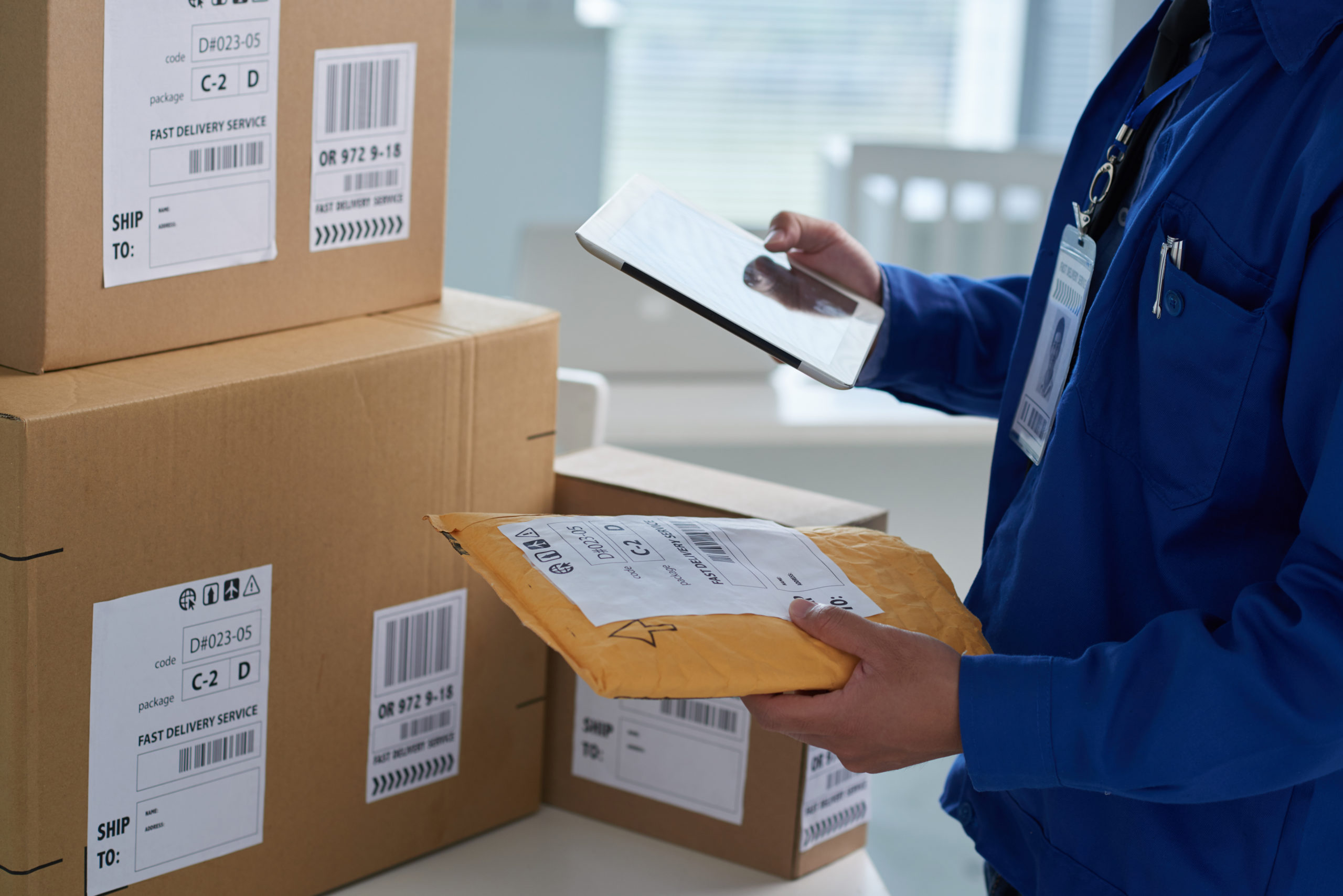 Close-up image of mail worker checking information on parcels